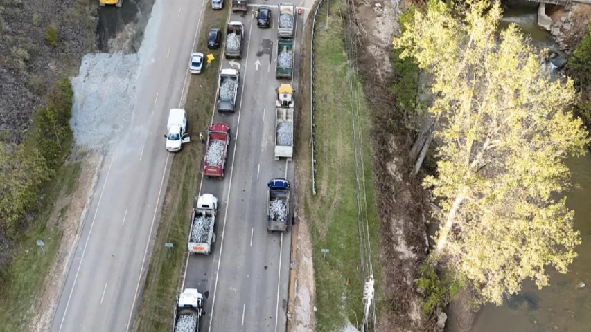 Lines of trucks on the highway Oct. 2 wait to dump gravel to build a temporary truck bridge across the river to get the Baxter North Cove facility back online.