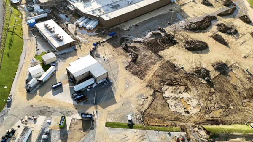 Mud and debris in the employee parking lot being pushed into piles for removal at the Baxter North Cove facility to get the site back online. Photo by Aerial Lens