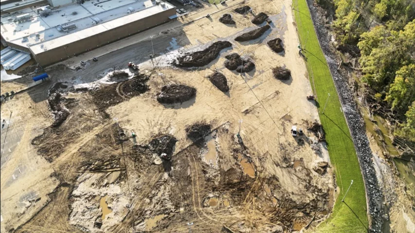 Mud and debris in the employee parking lot being pushed into piles for removal at the Baxter North Cove facility to get the site back online. Photo by Aerial Lens