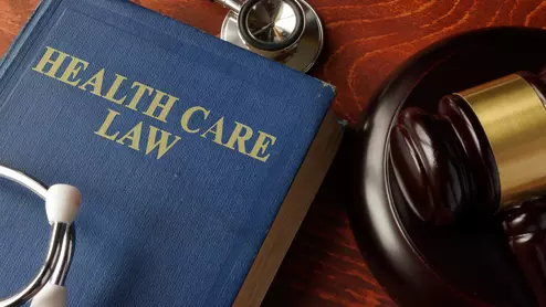 A book titled "Health Care Law" next to a gavel and a stethoscope