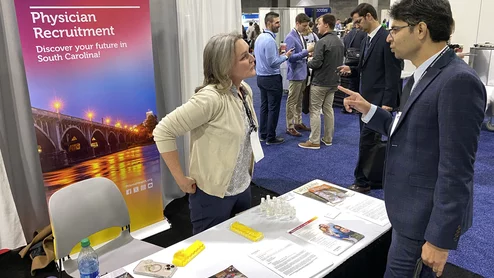 A recruiter from Prism Health in South Carolina speaks with an ACC.24 attendee on the expo floor. There is a growing shortage of general cardiologists and recruiters say it is getting more difficult to attract individuals to rural areas. Photo by Dave Fornell. #ACC24 #ACC2024