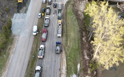 Lines of trucks on the highway Oct. 2 wait to dump gravel to build a temporary truck bridge across the river to get the Baxter North Cove facility back online. 