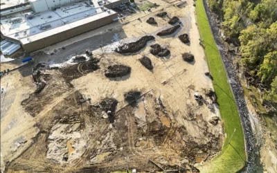 Mud and debris in the employee parking lot being pushed into piles for removal at the Baxter North Cove facility to get the site back online. Photo by Aerial Lens